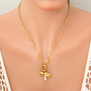 Close-up of golden paperclip chain necklace with heart, pearl, and starfish charms