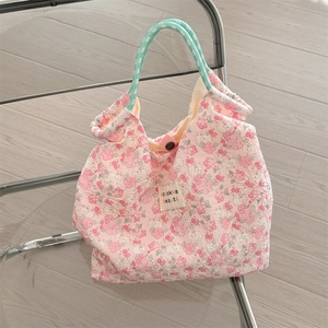 Detail of pink floral canvas tote bag featuring mint green rope handles and zakka label