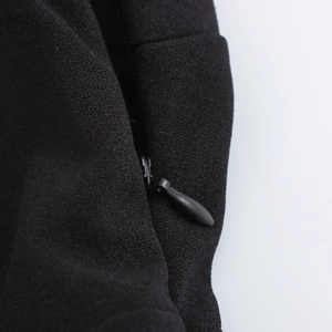 Dettaglio ravvicinato di una cerniera invisibile su un abito nero con texture