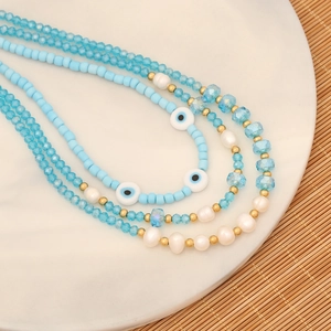 Multilayer evil eye necklace with blue glass beads and pearls on a white plate