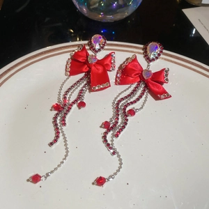 Detail of red bow earrings with long tassels, crystal hearts, and silver metal chains