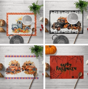 Detail of Halloween linen placemats showing autumn pumpkin and truck prints on a wooden table