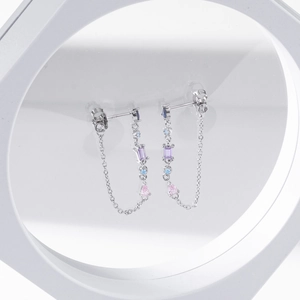 Macro detail of silver tassel earrings with colorful zirconia stones on a white ring