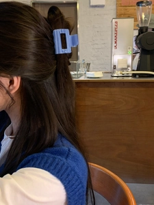 Blue square acetate hair claw clip shown in a half-up hairstyle at a cafe