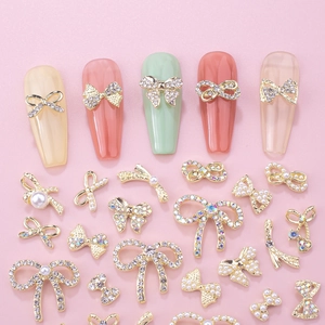 Detail of bow-shaped alloy nail charms with pearls and rhinestones on assorted nail tips