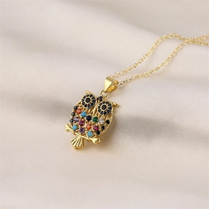 Detailed macro shot of a gold owl pendant featuring colorful inlaid zircon gemstones