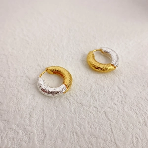 Two-tone gold and silver earrings with irregular lava texture and a minimalist hoop design