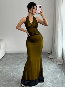 Detail of a dark green satin dress with waist pleats and fish tail mesh hemline