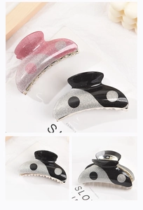 Detail of yin-yang style acrylic hair claws with glittery pink and black finishes