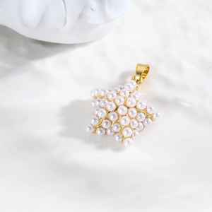 Élégant pendentif étoile dorée incrusté de perles sur fond texturé blanc