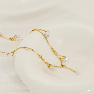 Gold stainless steel necklace with round zircon tassels displayed in a white bowl