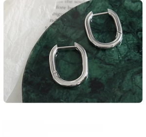 Macro shot of polished silver U-shape geometric earrings on a marble tray