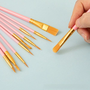 Detailed view of 10 pink nylon brushes with golden ferrules and orange synthetic bristles