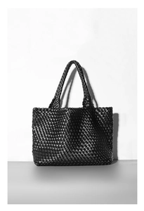 Close-up of black woven leather tote bag texture with minimalist double handles on white background