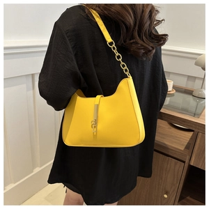 Close-up of bright yellow half-moon underarm bag with gold piston clasp and chain strap