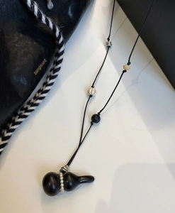 Detailed macro view of matte black hulu pendant with white pearls on a wax rope necklace