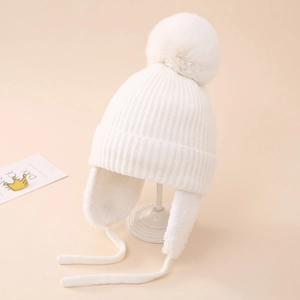 Détail du bonnet d'hiver blanc avec protège-oreilles, pompon et lanières tressées