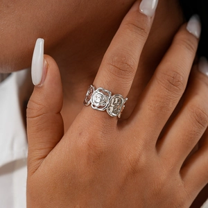 Gros plan d'une bague fleur en argent avec texture de métal martelé sur une main