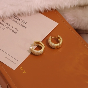 Close-up of gold plated huggie earrings with pave micro-set cubic zirconia on leather