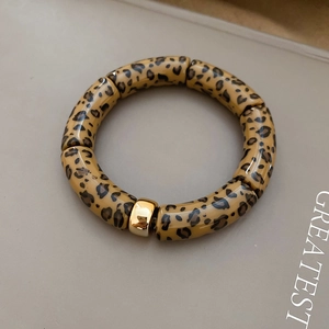 Detailed view of leopard print tube beads with a polished gold metal spacer on a bracelet