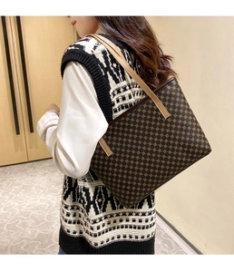 Detailed view of vintage monogram tote bag with brown floral patterns and leather straps