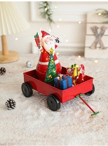 Close-up of red metal sled featuring Santa Claus and a green Christmas tree holiday ornament