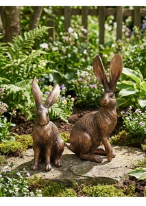 Pareja de esculturas de conejos realistas con acabado en bronce antiguo en jardín