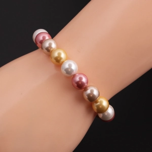 Close-up of a multi-color gradient pearl bracelet with white, pink, and gold beads