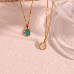 Detailed macro shot of gold teardrop necklaces with blue and white cat-eye stones