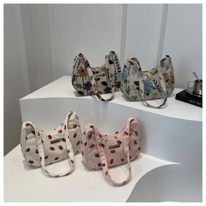 Chic floral jacquard and strawberry corduroy underarm bags on a white display stand