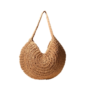 Minimalist light brown woven straw tote bag with round base for beach vacation styling