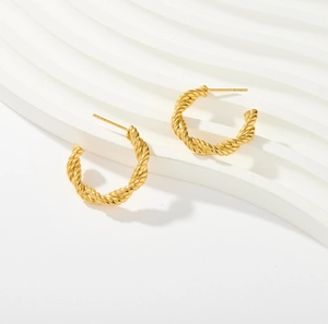 Detail shot of 18K gold C-shaped earrings with twisted texture on a white background