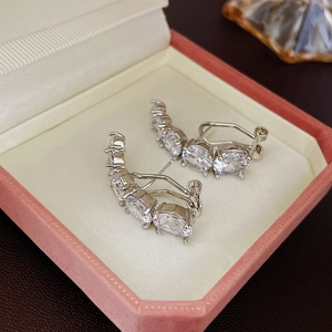 Gros plan sur des boucles d'oreilles courbées en argent et zircons dans un écrin