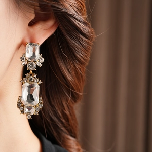 Close-up of vintage geometric gold earrings with clear crystals worn by a model