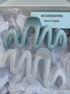 Detail showing blue and cream wavy hair clips with a glossy resin finish for women