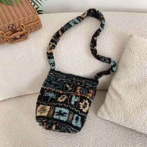 Close-up of plush knit bucket bag with colorful geometric patterns on a soft sofa