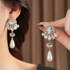Detail of flower rhinestone earrings with drop pearl on model and close-up view