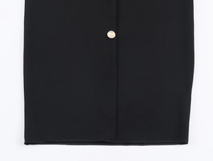 Detailed macro of a black midi dress featuring a gold metal button and smooth fabric texture