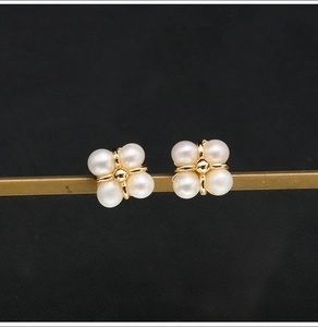 Detailed macro view of gold flower-shaped earrings featuring eight white freshwater pearls