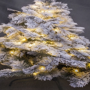 Detail of pre-lit flocked Christmas tree with realistic snow and warm LED lights