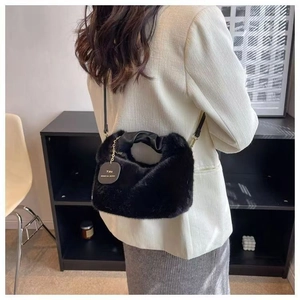 Detail of a black plush handbag with a ruffled handle and 'You' label on a model