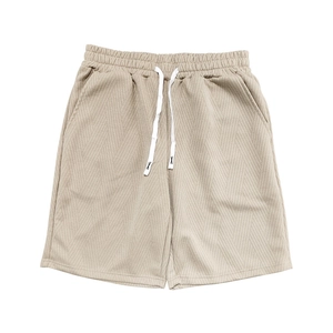 Détail du short en tricot beige pour hommes montrant la texture gaufrée et le cordon de serrage
