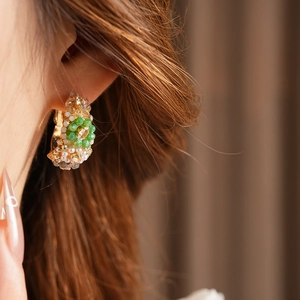 Close-up of vintage style hoop earring with green glass beads and small pearls on model