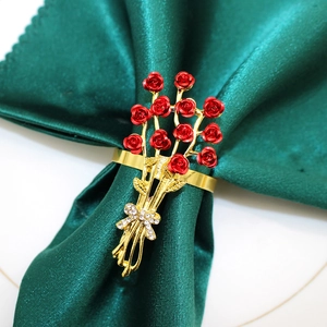 Golden rose bouquet napkin ring with red flowers and rhinestone bow on green fabric