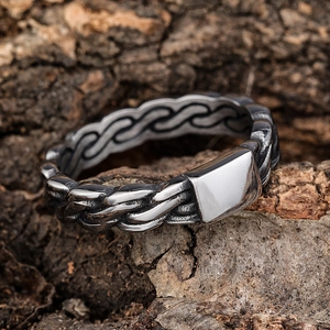 Punk style silver stainless steel ring with woven texture on a natural bark background