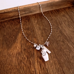 Detail of luxury beaded necklace with bear motifs and engraved silver bar on dark wood