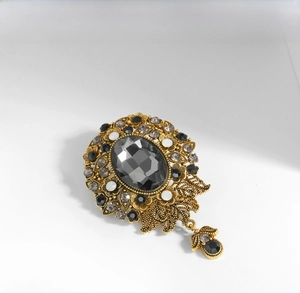 Detail of vintage gold brooch featuring gray faceted gem and rhinestone floral patterns