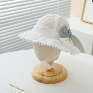 Detailed view of white lace baby sun hat with a grey polka dot bow on a stand.