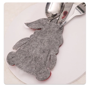 Close-up of grey felt bunny cutlery holder with stitched details on a white plate