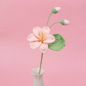 Gros plan d'un lys rose fait main au crochet avec étamines jaunes et boutons verts